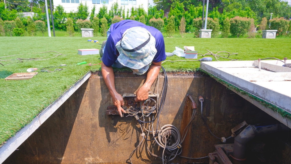 Plumber inspecting a sump pump not working during heavy rain to prevent basement flooding